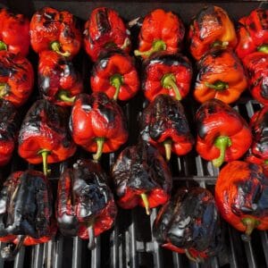 A close-up of grilled red bell peppers with blackened grill marks, showcasing their vibrant color and smoky flavor.